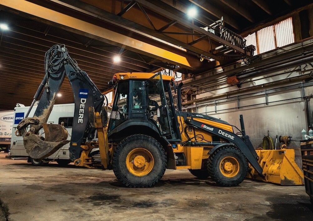 John Deere backhoe loader boom with hydraulic cylinders and lines, in for service at Mach 6