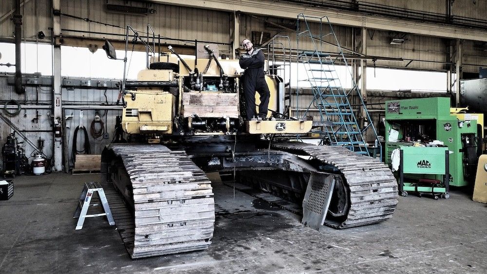 Mach 6 technician standing on tracked equipment undergoing service