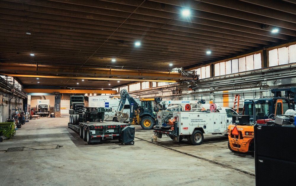 A wide row of fleet vehicles and equipment being serviced inside the Mach 6 Edmonton shop