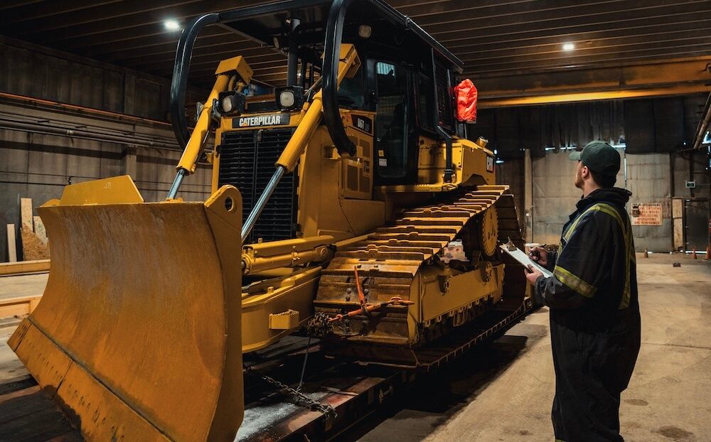 Mach 6 technician inspecting a CAT dozer with a clipboard